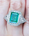 Toma cercana de un anillo con esmeralda cuadrada y diamantes rodeándolo hecho en oro blanco,