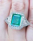 Toma cercana de un anillo con esmeralda cuadrada y diamantes rodeándolo hecho en oro blanco,