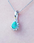 A white gold necklace with a teardrop emerald pendant on a light skin background.
