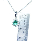 Colombian emerald enhancer pendant on a chain with a ruler for scale on a white background.