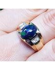 Men's 14K yellow gold ring with a dark Ethiopian black opal and small white accent stones.