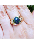 Men's 14K yellow gold ring with a vibrant oval Ethiopian black opal and two square accent stones.