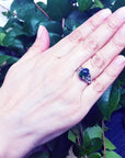 Woman's hand wearing a sterling silver ring with a 2.15 ct black Ethiopian opal, showing green-blue play of color.