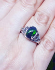 Sterling silver ring with a 2.15 ct oval black Ethiopian opal showing green-blue play of color, worn on a finger.