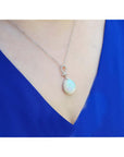 Ethiopian Welo opal and diamond pendant in 14K white gold on a woman's neck.