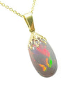 Ethiopian Welo opal pendant with vibrant red and rainbow fire in a 14k yellow gold setting.