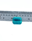 Certified 3.98 ct emerald-cut Muzo emerald with vibrant bluish-green hue, shown next to a ruler for scale.