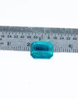 Certified 3.98 ct emerald-cut Muzo emerald with vibrant bluish-green hue, shown next to a ruler for scale.