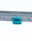 Certified 3.98 ct emerald-cut Muzo emerald with vibrant bluish-green hue, shown next to a ruler for scale.