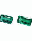 Two sparkling, emerald-cut natural emeralds with a medium deep bluish-green hue.