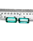 Two emerald-cut, medium deep bluish-green natural emeralds, a matching pair, displayed against a ruler.