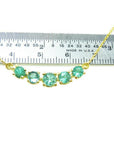 Green Fire Emerald Necklace with five sparkling round cut emeralds on a 14K gold chain, measured against a ruler.