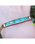 14K gold bracelet with five vibrant bluish-green emeralds and sparkling diamonds on a wrist.