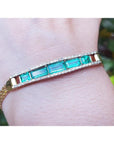 14K gold bracelet with five vibrant bluish-green emeralds and sparkling diamonds on a wrist.