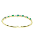 Flexible 14K yellow gold bangle with oval emeralds and accent diamonds.