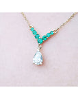 Women's necklace Tear drop natural diamond dangling from a V style center piece with natural round cut emeralds