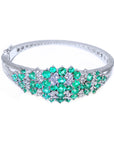 Jewelry with natural emerald and diamonds and a white gold band on a white background.