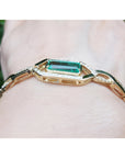 14K yellow gold bracelet with a rectangular emerald and diamond accents on a wrist.