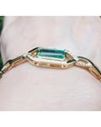 14K yellow gold bracelet with a rectangular emerald and diamond accents on a wrist.