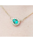 Vibrant pear-shaped emerald necklace with diamond halo on a 14K yellow gold chain.