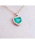 14K gold pendant with a vibrant green Colombian emerald and diamond halo.