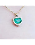 14K gold pendant with a vibrant green Colombian emerald and diamond halo.