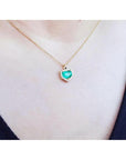 Colombian emerald pendant with diamond halo on a thin 14K gold chain, worn on a person.