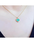 Colombian emerald pendant with diamond halo on a thin 14K gold chain, worn on a person.