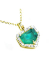 Yellow gold pendant with a natural emerald and diamond accents on a toside view.