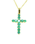 Yellow gold cross with round cut natural colombian emeralds showing its topside view.