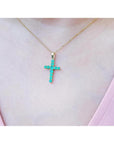 18K yellow gold cross pendant necklace with genuine emeralds on a woman's chest.