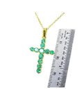 1.15 ct. genuine emerald cross pendant necklace in 18K yellow gold, shown with a ruler for scale.