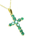 A 18k yellow gold emerald cross pendant necklace on topside position view.