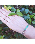 14k white gold bracelet with vibrant Colombian emeralds and princess-cut diamonds on a woman's wrist.