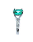 A bridal's cushion cut emerald and trapezoid side diamond ring in 18k white gold, side profile visible.