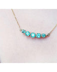 14K gold necklace with five round, medium light green Colombian emeralds, graduated in size.