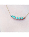 14K gold necklace with five round, medium light green Colombian emeralds, graduated in size.