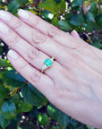 1.51 ct. emerald and trillion cut diamonds ring in 18k gold on a hand.