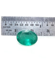 3.68 ct GIA certified loose oval emerald, bright bluish-green, displayed with a ruler for scale.
