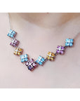 18K white gold necklace with tri-colored topaz X-cluster links on a model's neck.