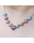 18K white gold necklace with tri-colored topaz X-cluster links on a model's neck.
