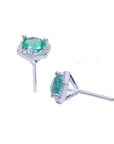 Round cut Colombian emerald stud earrings in 14K white gold with a hexagonal diamond halo.