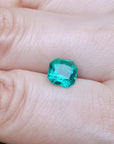2.45 ct. GIA certified Asscher cut emerald with vibrant bluish-green color on a person's hand.