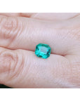 2.45 ct. GIA certified Asscher cut emerald with vibrant bluish-green color on a person's hand.