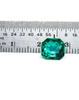 2.45 ct GIA certified Asscher cut emerald, vibrant bluish-green, next to a ruler for scale.