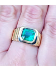 A GIA certified natural colombian emerald men's ring crafted in 18k yellow gold on a hand.