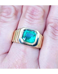 A GIA certified natural colombian emerald men's ring crafted in 18k yellow gold on a hand.