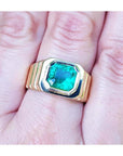 A GIA certified natural colombian emerald men's ring crafted in 18k yellow gold on a hand.