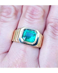 A GIA certified natural colombian emerald men's ring crafted in 18k yellow gold on a hand.