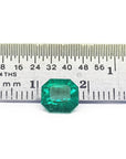 GIA certified 1.40 carat emerald-cut Colombian emerald with sparkling bluish-green color, next to a ruler.
